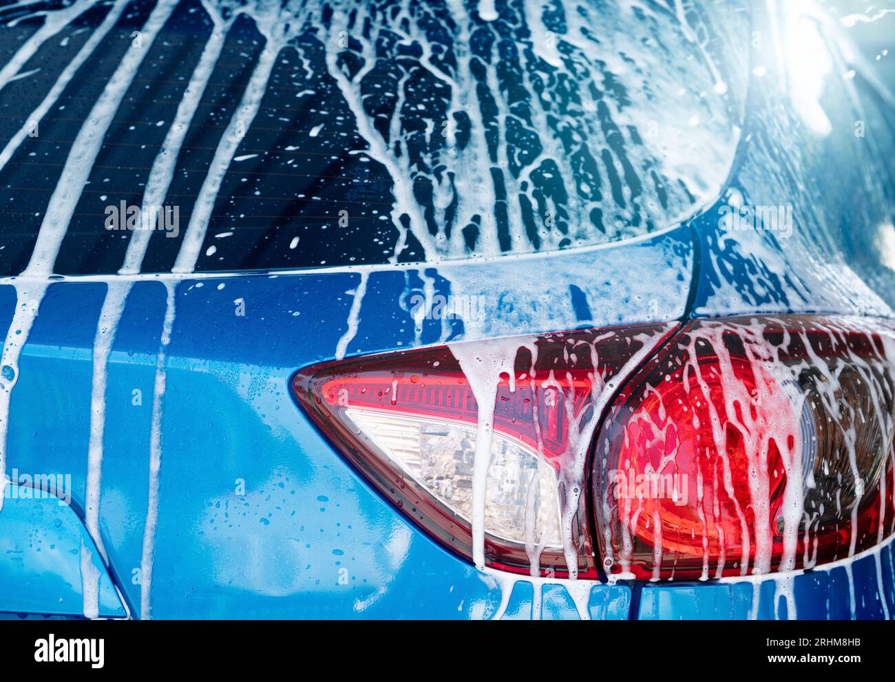 Blue car wash with white soap foam and professional auto care service