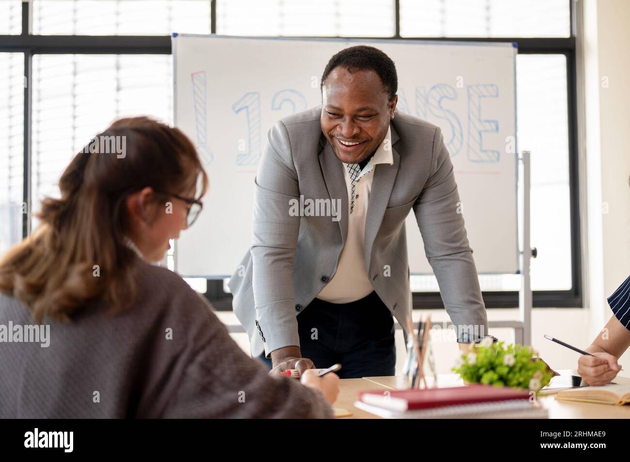 A kind African American male English teacher or tutor is enjoying a conversation with an Asian student during the class. Diversity, education, languag Stock Photo