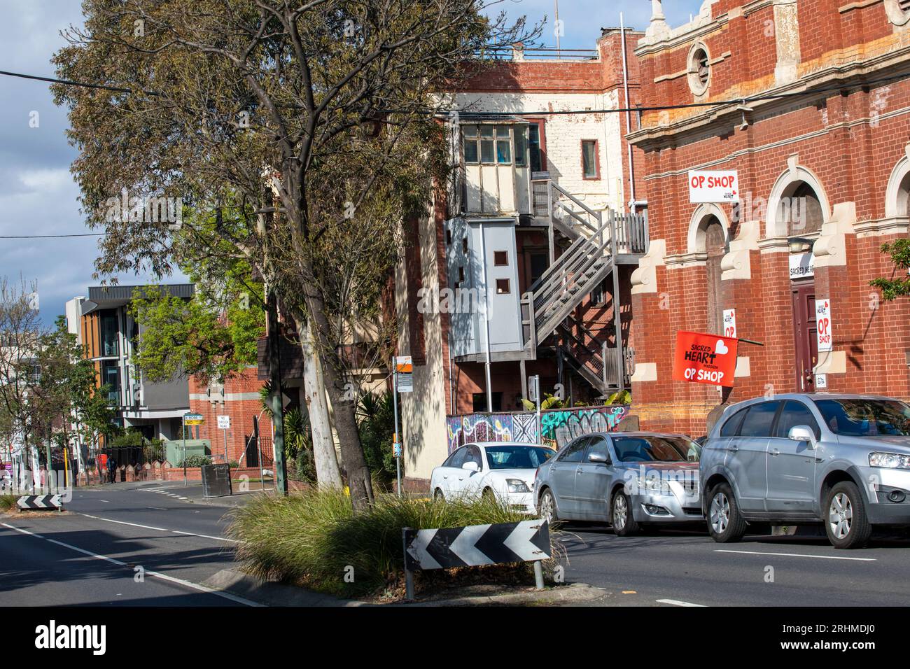 Street view in Grey Street, St Kilda with cars, the Scared heart mission, other housing and median strip with gum trees. Stock Photo