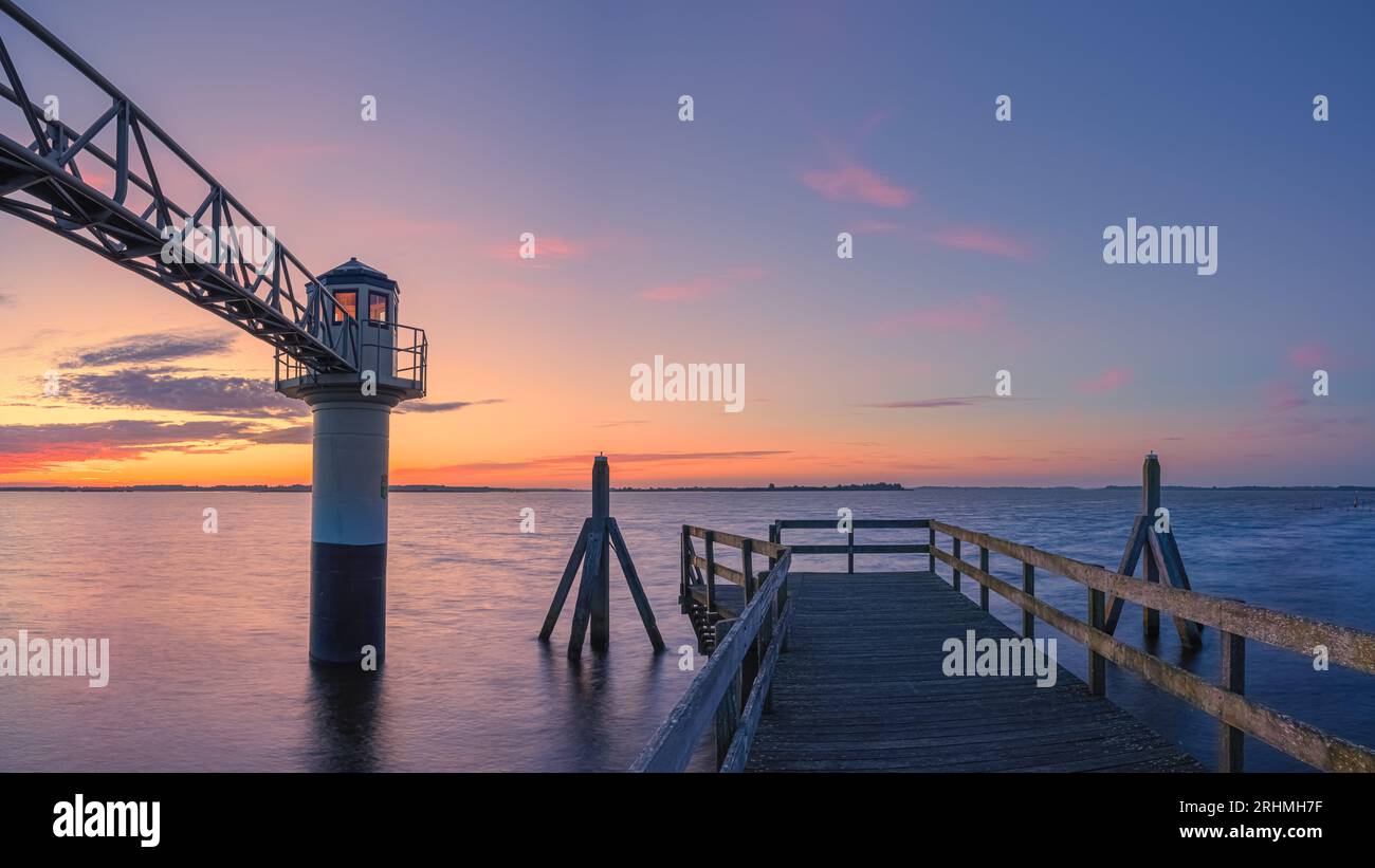 A horizontal 16:9 photo of a summer sunrise at the lighthouse in Oostmahorn. However, the name lighthouse is not appropriate here, because it is a mea Stock Photo