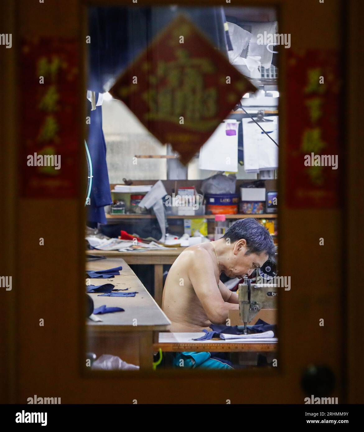 August 18, 2023, Hong Kong, Hong Kong, Hong Kong: A tailor operates a traditional sewing machine inside a mini clothes factory at Mirador Mansion ''“ a historic building comprised of residences, affordable guesthouses and small-scale businesses. Tailor businesses of this kind in Hong Kong are on the edge of extinction as consumption habits have changed over the decades. The building on Nathan Road that features Hong Kong's densely populated population was established in 1959, where manufactures for watches or gloves and tailor shops there flourished during the industrialisation between the 50s Stock Photo