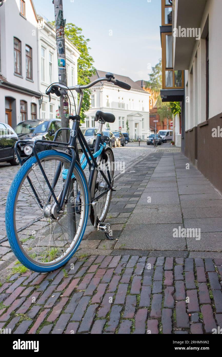 Classic bicycle with blue wheels on city street. Urban transport concept. Parking bike in town. Antique bike on street. Travel and tourism concept. Stock Photo