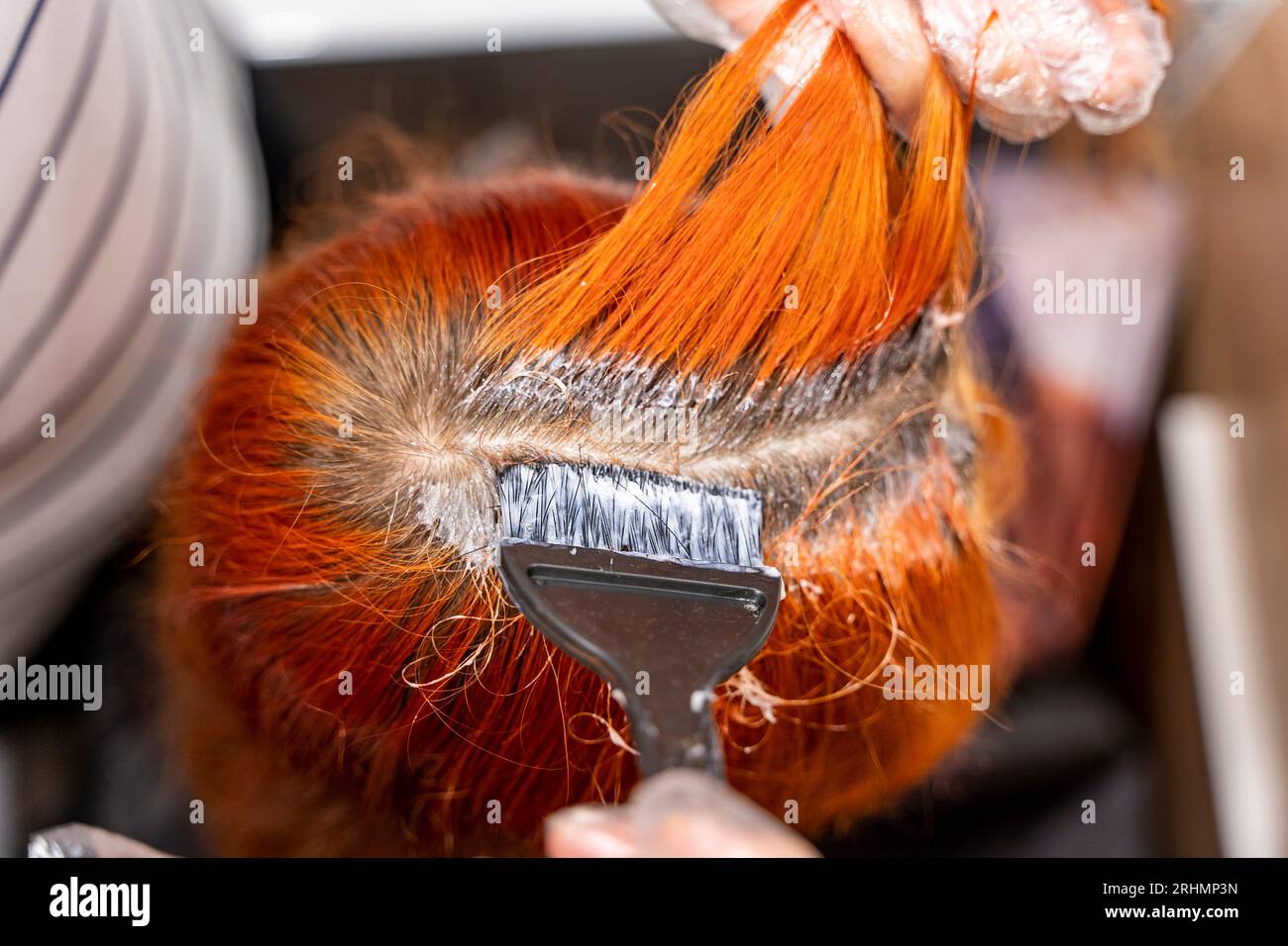 a teenage girl dyes her hair red. The process of dyeing hair red