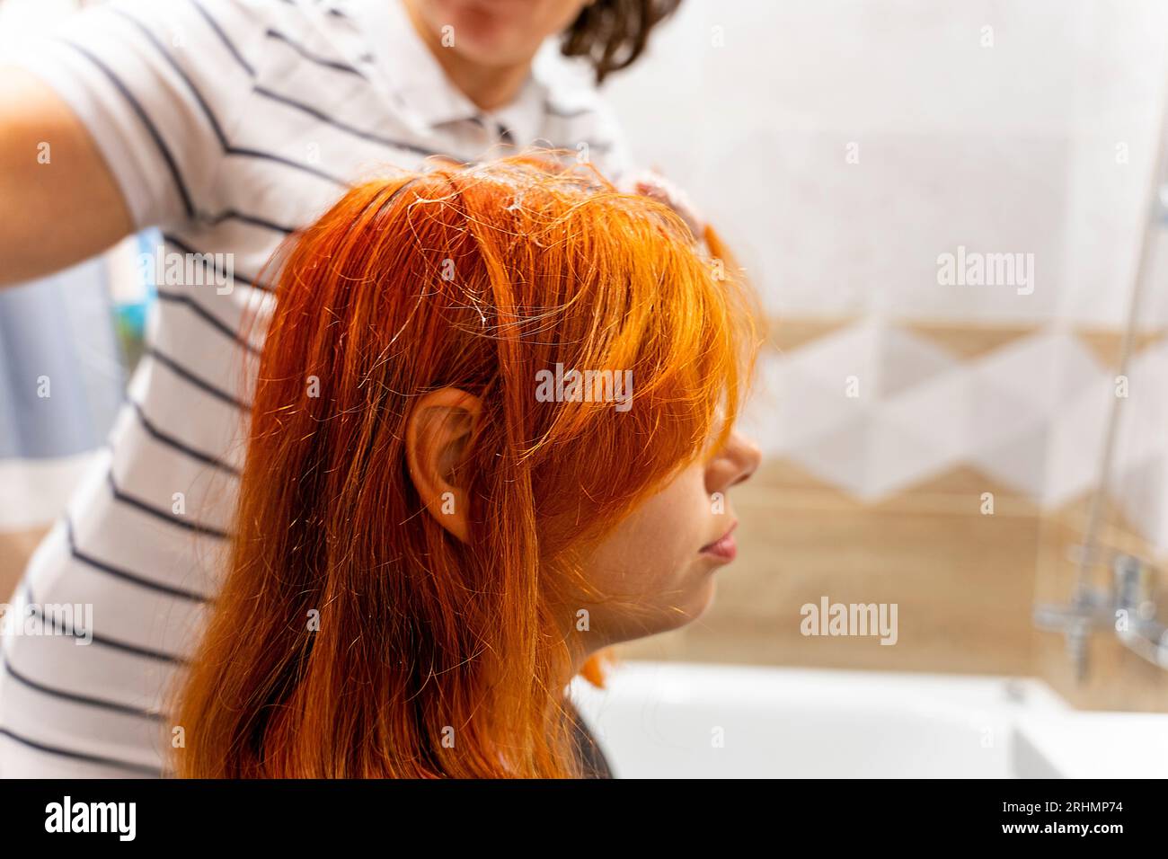 Profile of a pretty teenage girl coloring her hair red. The process of dyeing hair red. Style