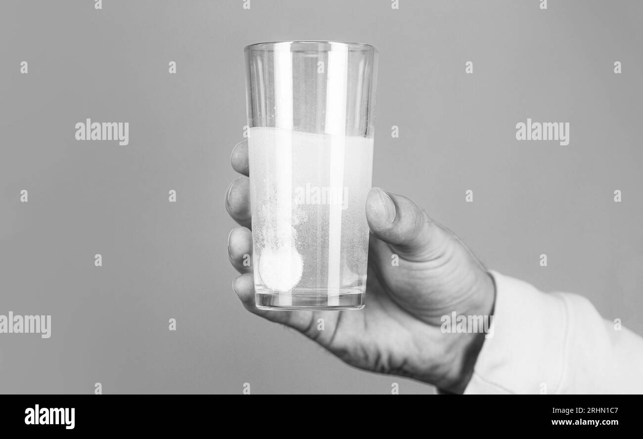 White pill and a glass of water in man hands. Health concept. Close up