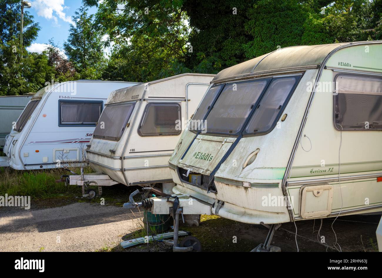 A row of mostly delapidated and dirty caravans parked at Lincoln Farm Truck Stop in Bassall Common, Solihull, West Midlands, UK. The truck stop and ca Stock Photo