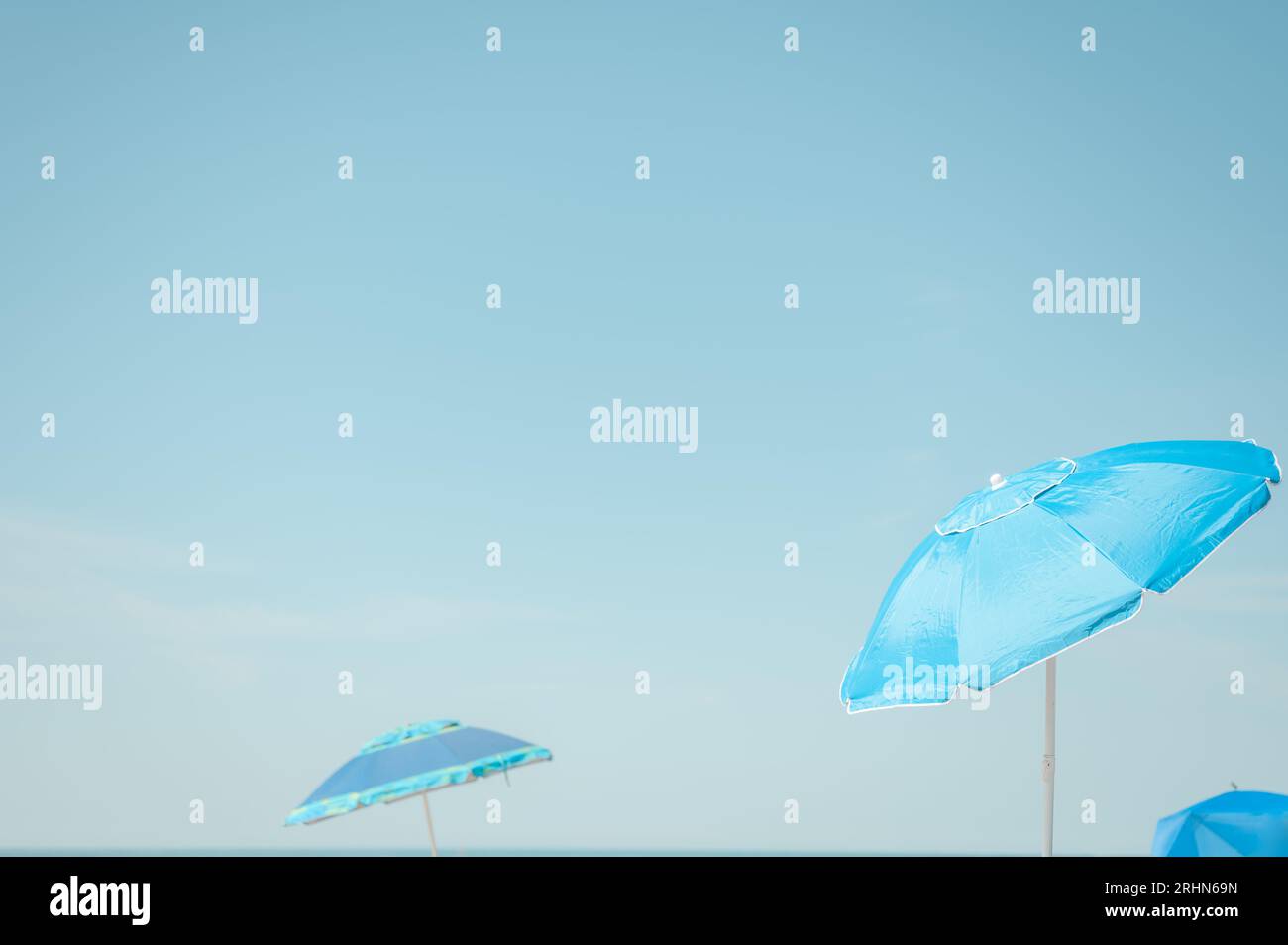 Blue beach umbrellas against blue sky at the beach Stock Photo