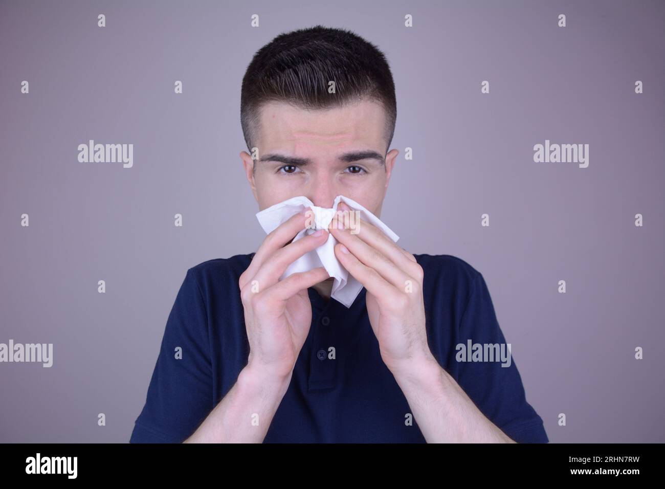 Young Caucasian Man with Runny Nose Uses Tissue due to Cold on Isolated