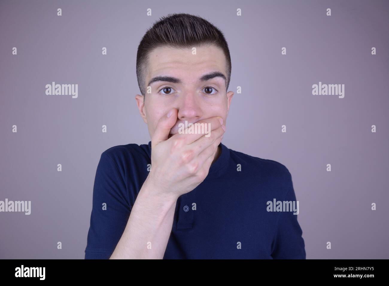 Handsome Caucasian Man Covering Mouth with Hand on Isolated Background Stock Photo