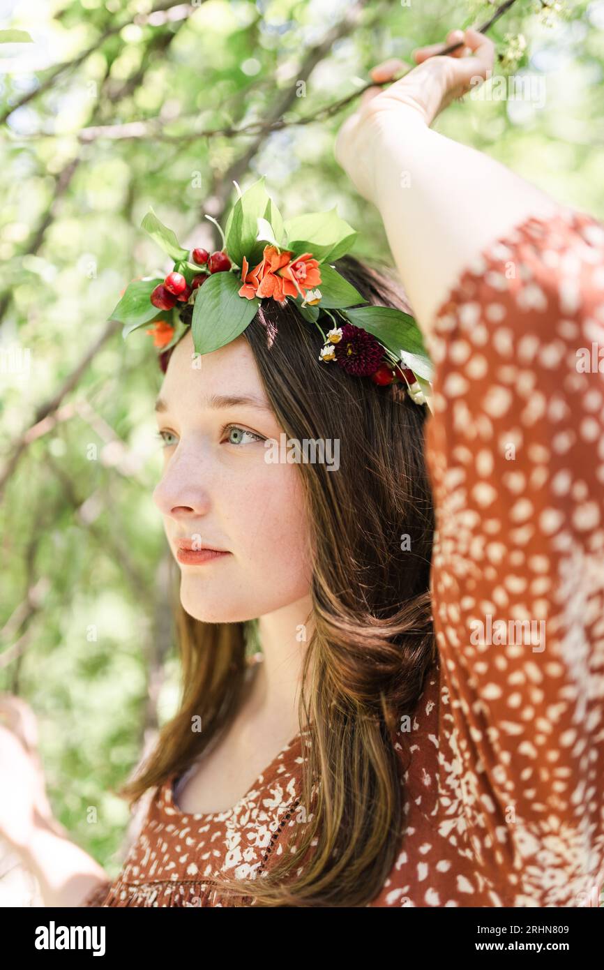 A woman with a flower crown grabbing a tree branch Stock Photo - Alamy