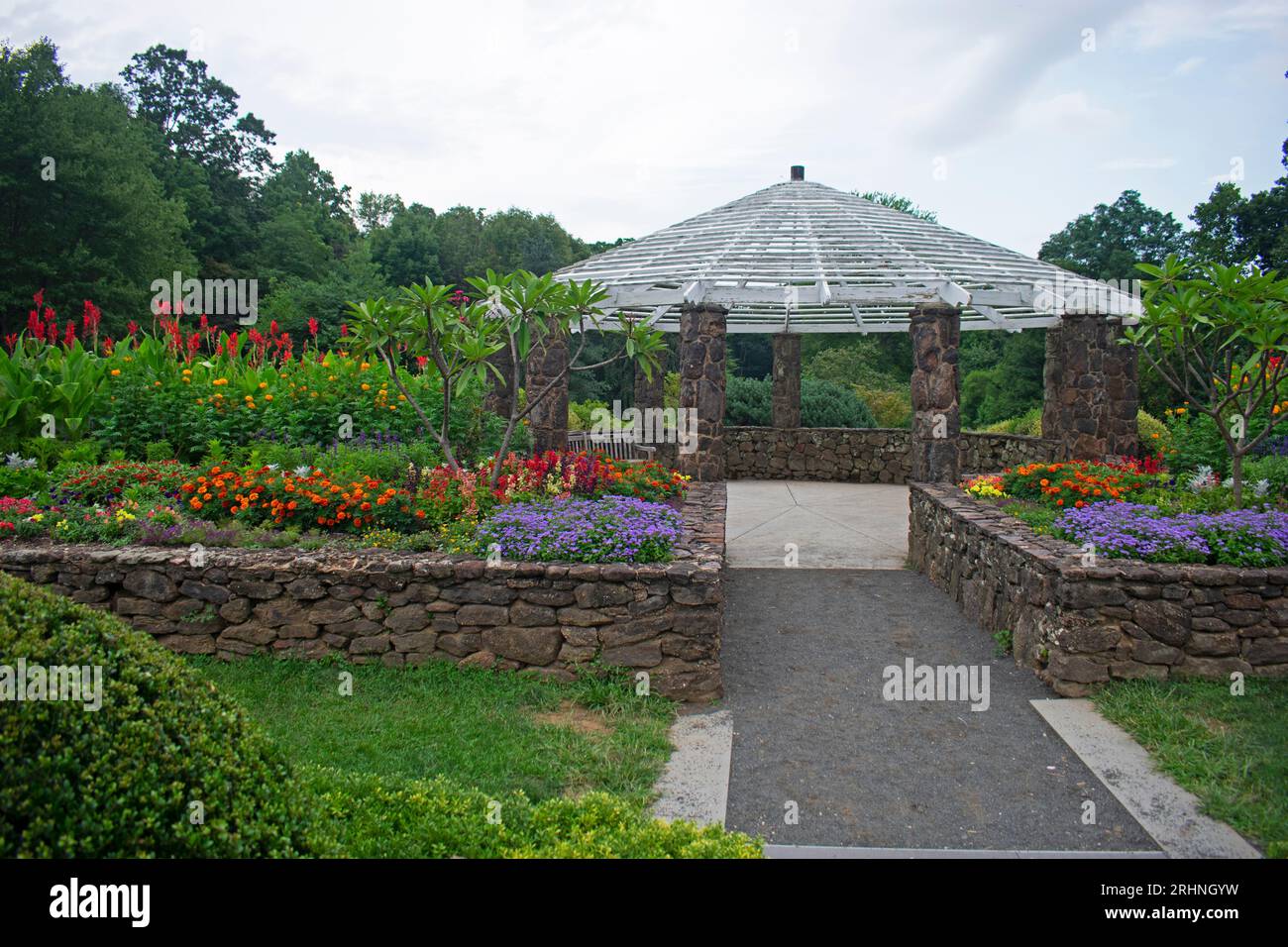 A pretty stone and wood gazebo at the end of a flower bed in a local garden park -15 Stock Photo