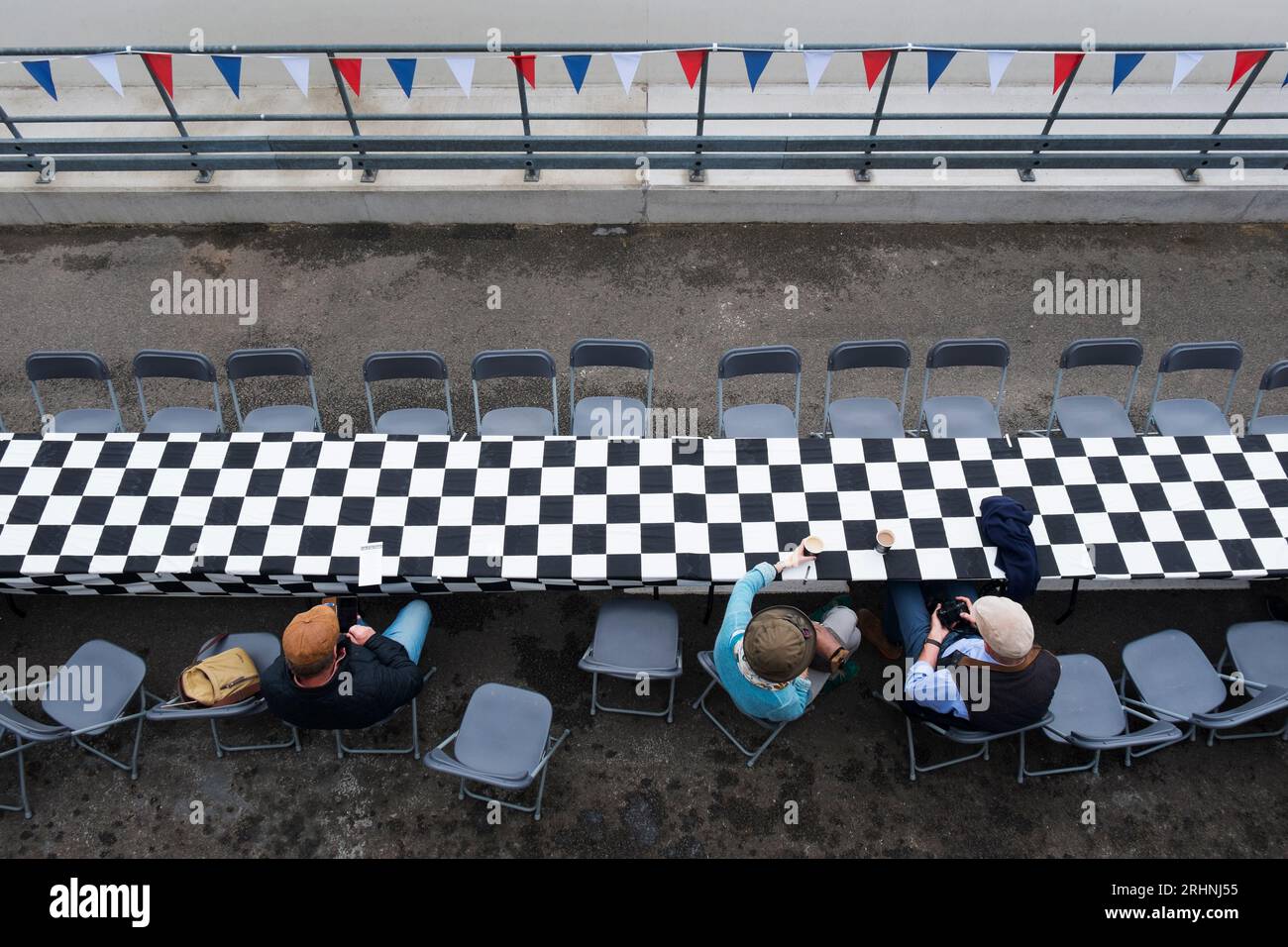 Enthusiasts sitting at tables in the Pit Lane at Rule Britannia Breakfast Club Meeting to celebrate the Queen's Platinum Jubilee, Goodwood circuit, UK Stock Photo