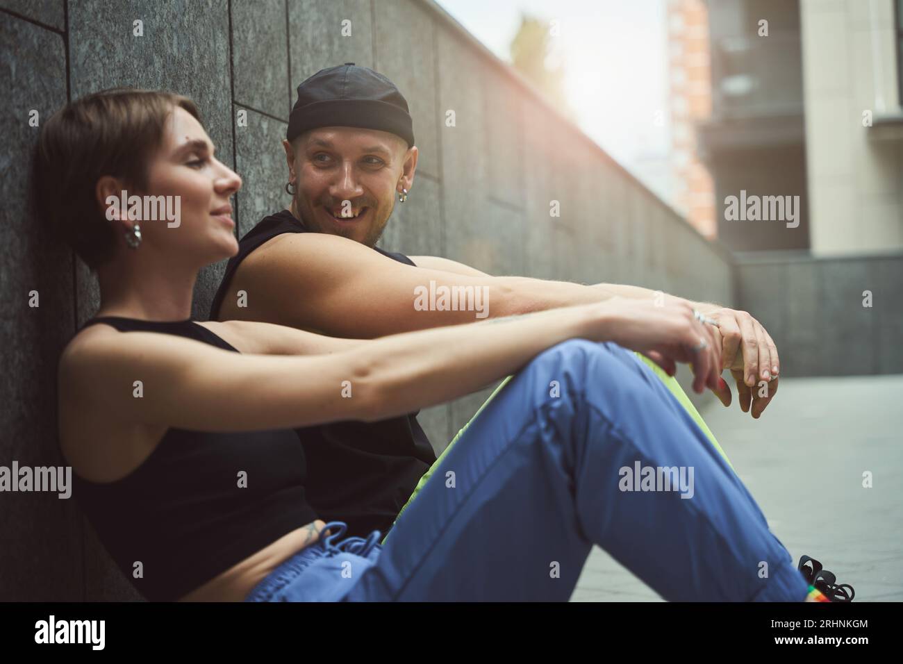Young informal man and his girlfriend chat while sitting on sidewalk Stock Photo