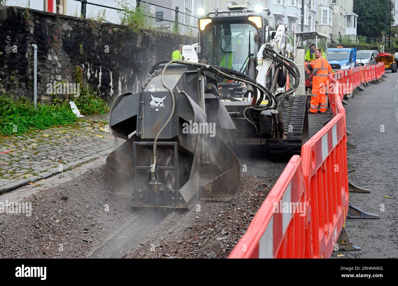 Trenching machine (Bobcat) being used for cutting channel through pavement  in street to lay duck work for fibre optic cable, UK Stock Photo - Alamy