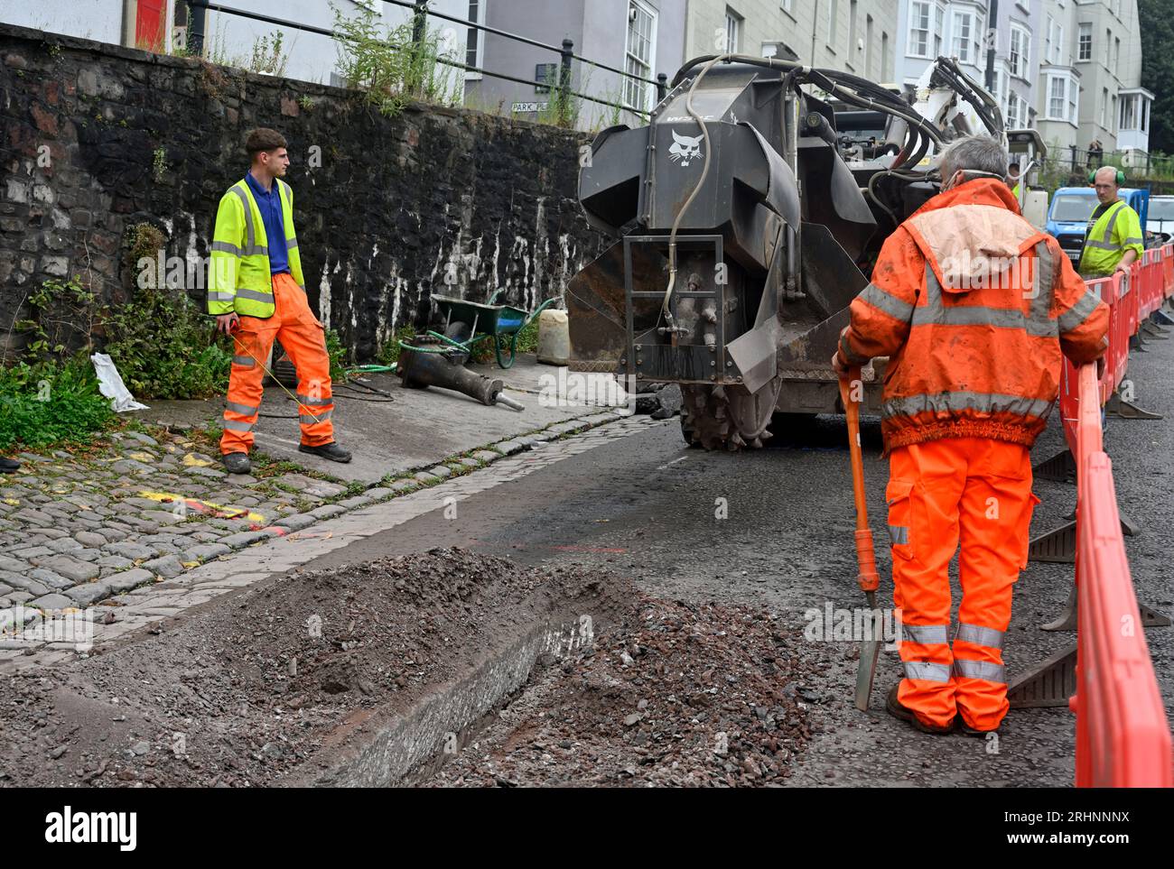 Trenching machine (Bobcat) being used for cutting channel through pavement in street to lay duck work for fibre optic cable, UK Stock Photo