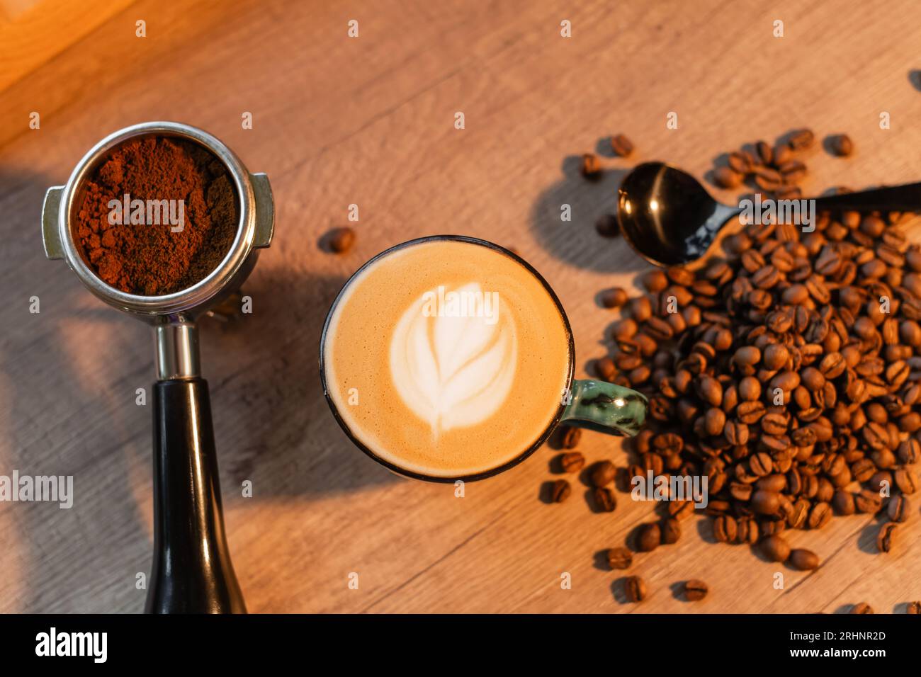 top view of cappuccino in cup near holder and coffee beans on worktop ...