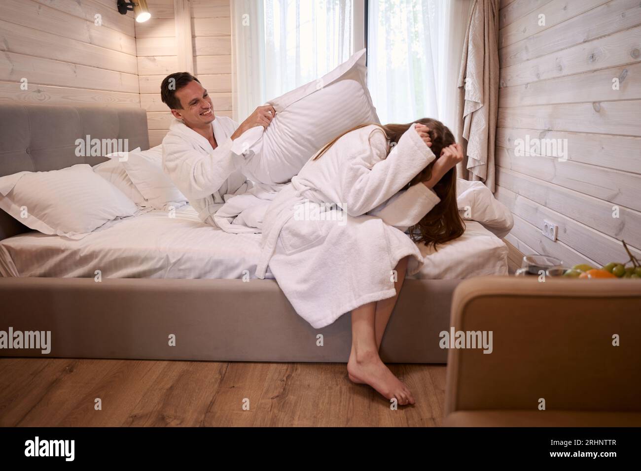 Man hitting woman with pillow while they sitting on bed Stock Photo Alamy