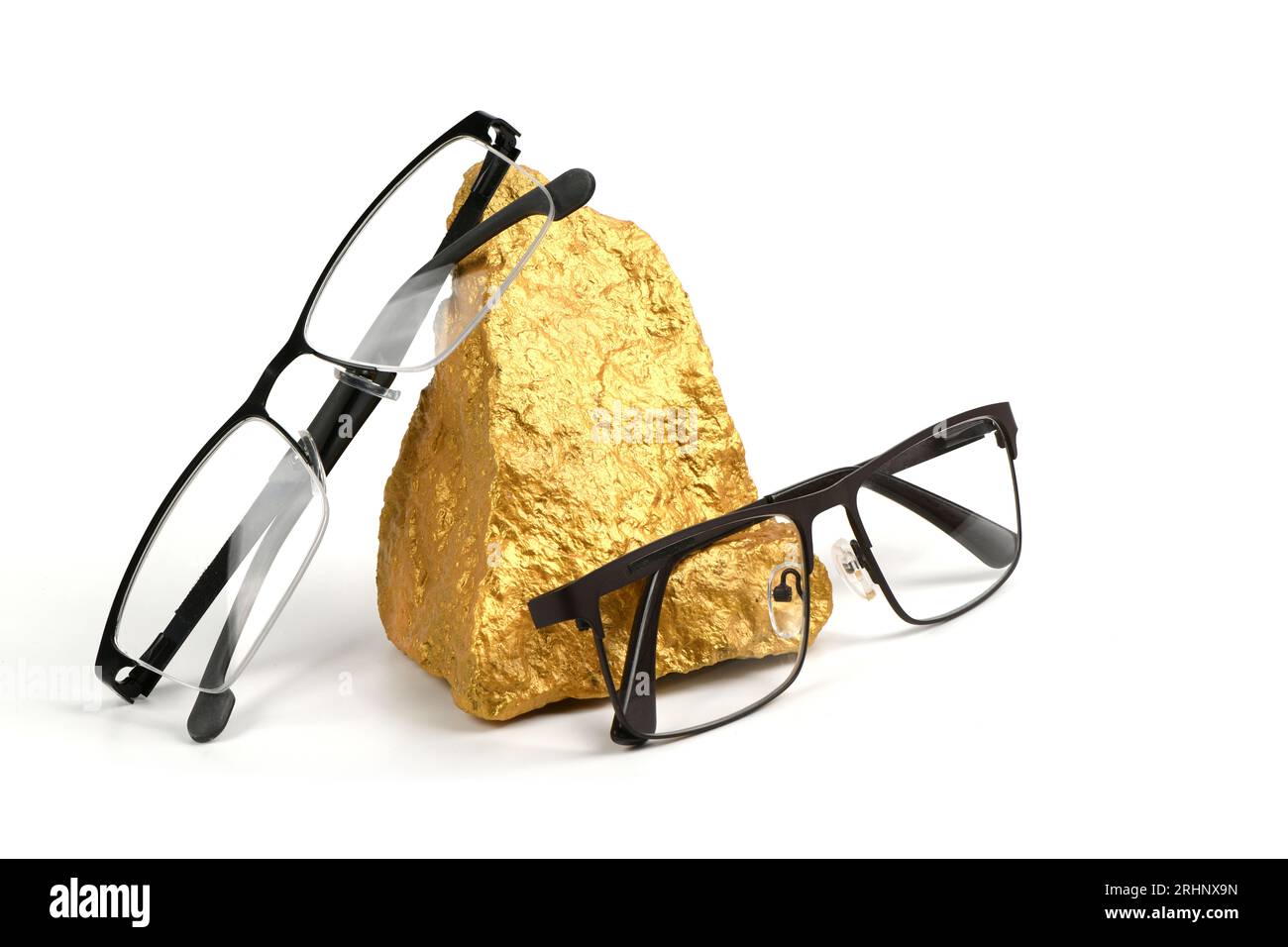 Pair of reading glasses on shining golden nuggets isolated on white