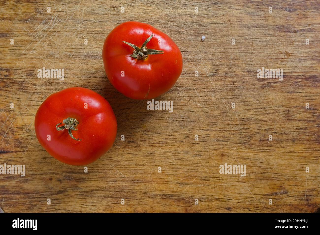 two ripe vine tomatoes on a woodgrain chopping board Stock Photo - Alamy