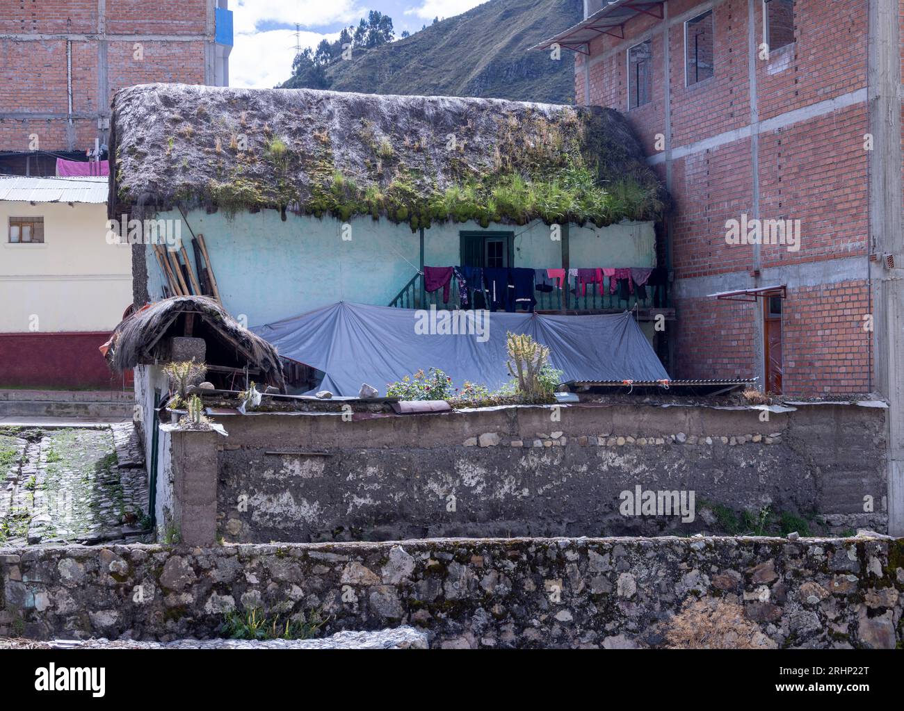 small thatched roof house beside later brick buildings, Catac, Peru, South America Stock Photo