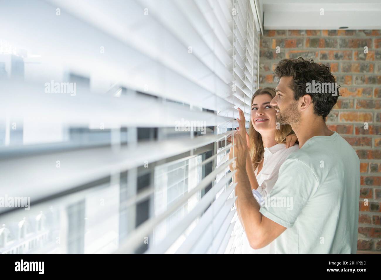 Couple looking through blind Stock Photo