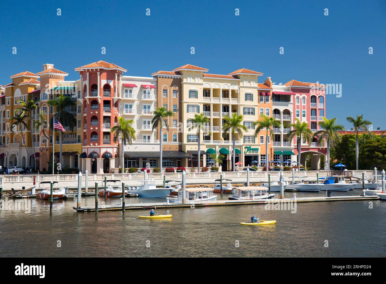 Naples, Florida, USA. View across the Gordon River to the colourful architecture of Bayfront Place, kayakers crossing the marina. Stock Photo