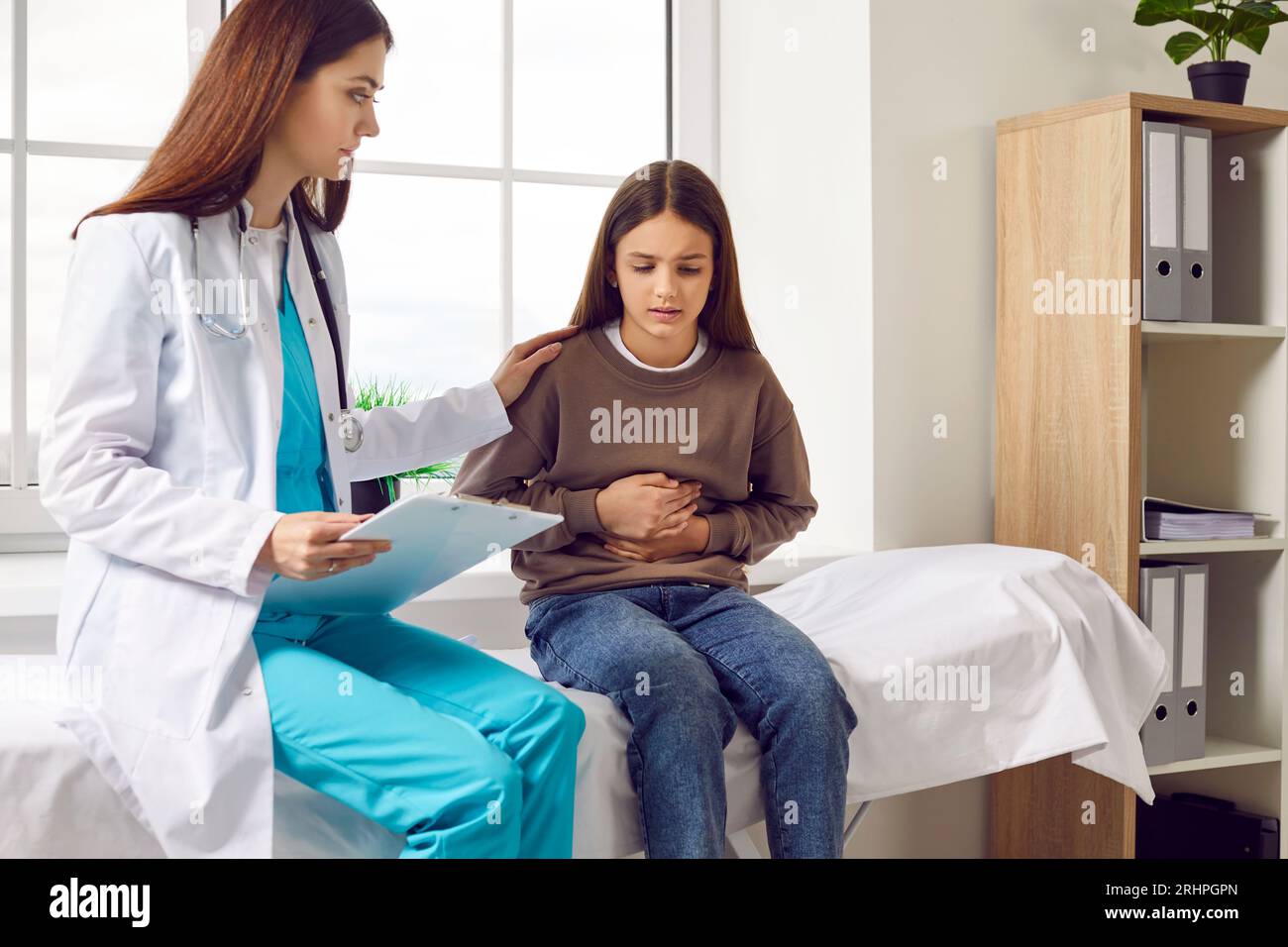 Child girl sitting in the doctor's office pointing to her stomach