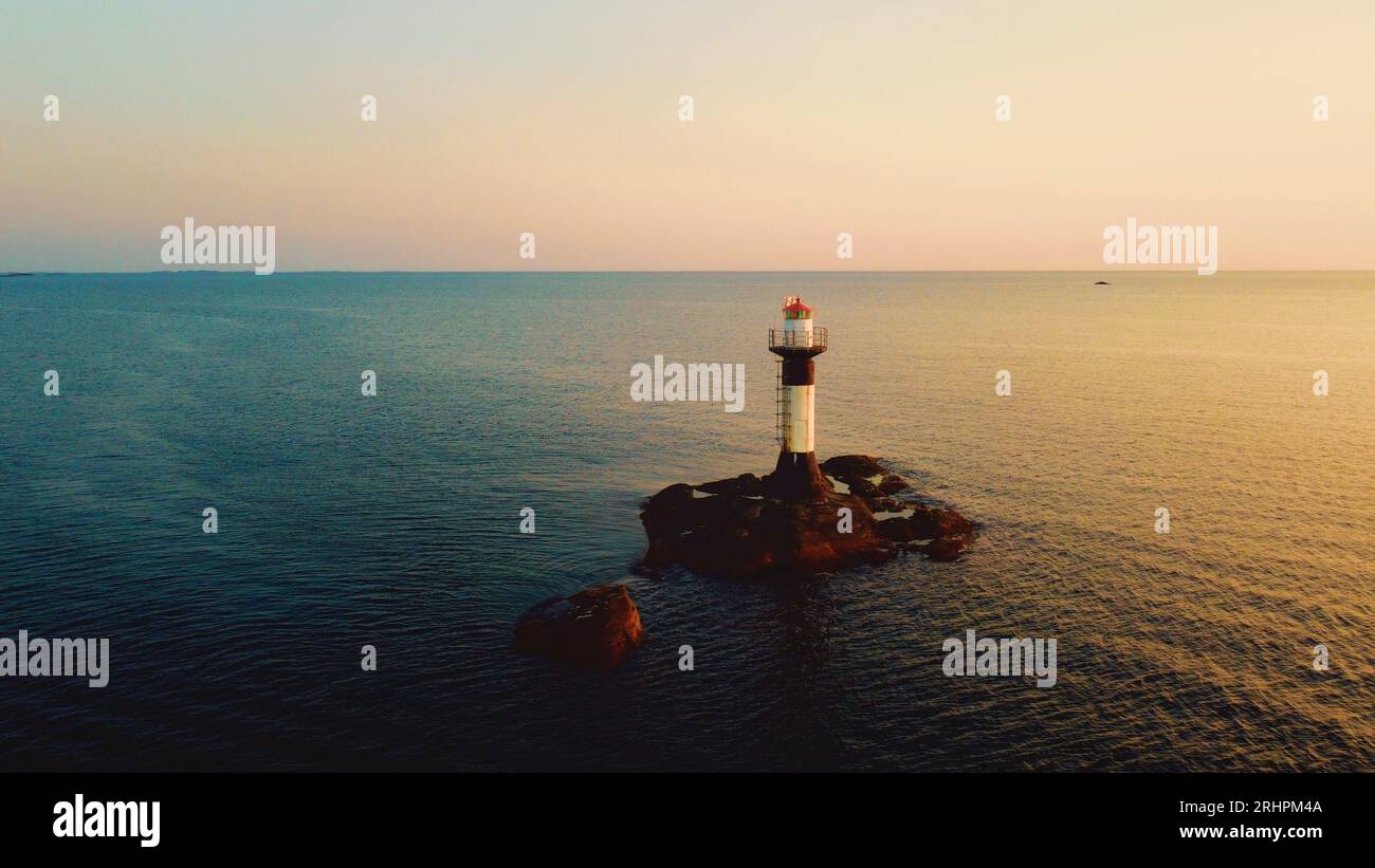 A drone photograph of Väcker Fyr, a lighthouse on the Swedish westcoast, taken at sunset. The lightouse standing on some rocks in the ocean. Stock Photo