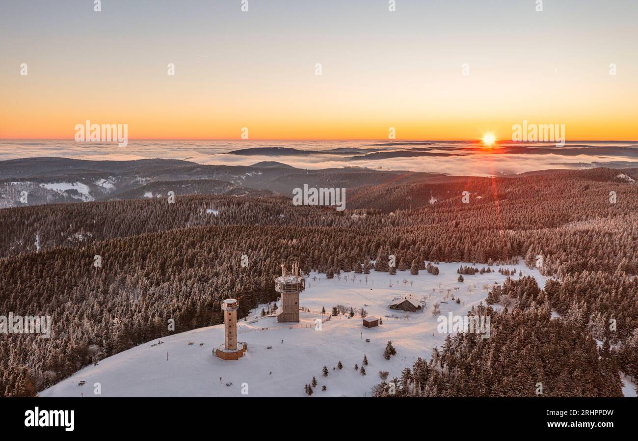Germany, Thuringia, Suhl, Gehlberg, Schneekopf (second highest mountain of Thuringian Forest), lookout and climbing tower, telecommunication tower, New Gehlberg Hut, forest, mountains, snow, sunrise, backlight, overview Stock Photo