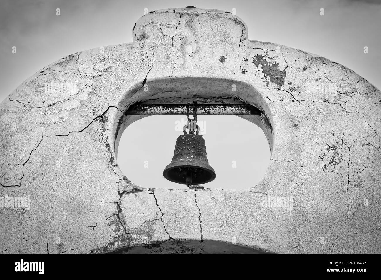 A bell hangs over a weathered cemetery gate near El Paso, Texas. Stock Photo