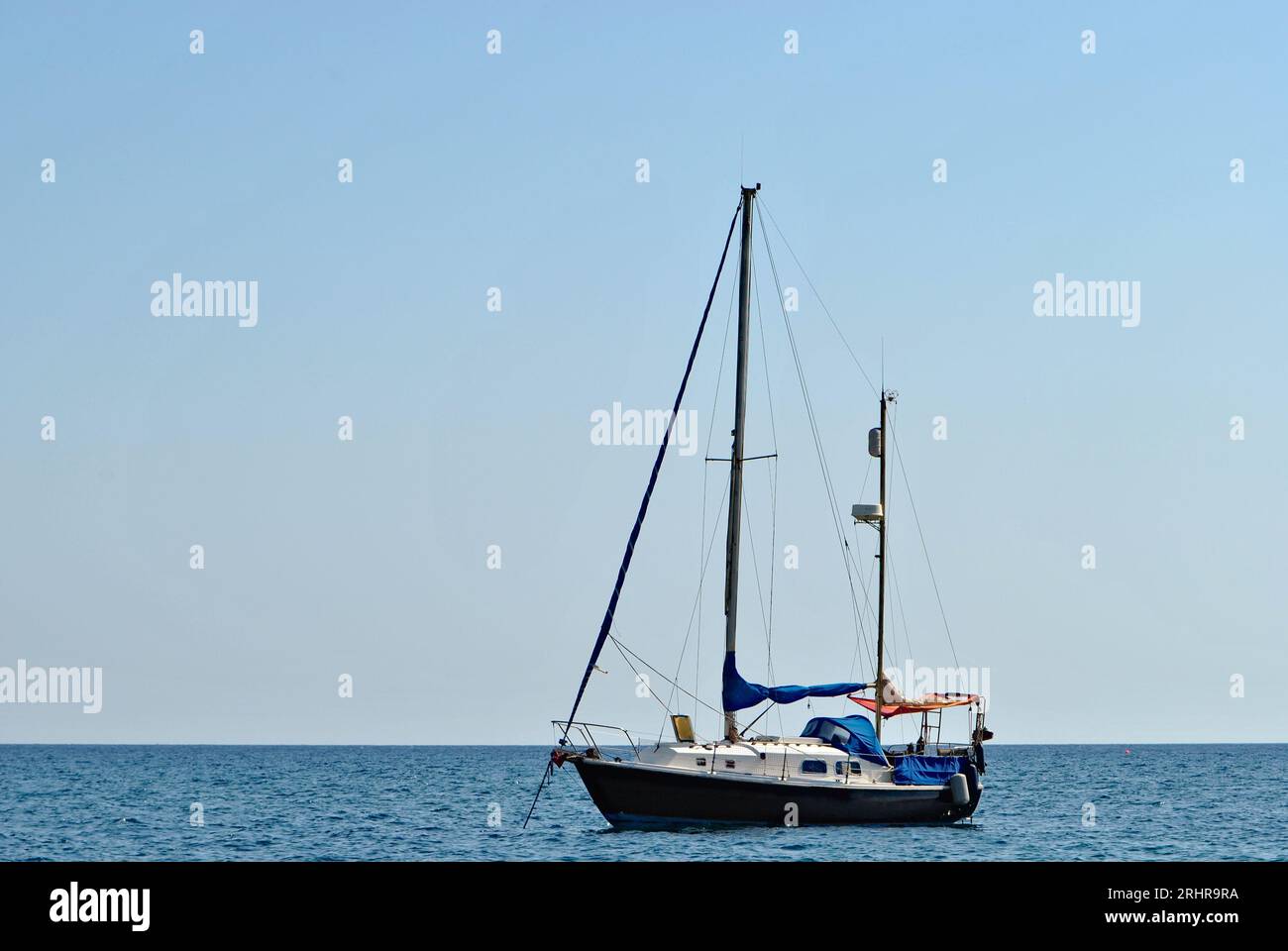 Sail boat on the horizon of the sea. Blurred blue background.  Negative space for text. Vacation on Santorini islands, Greece. Stock Photo