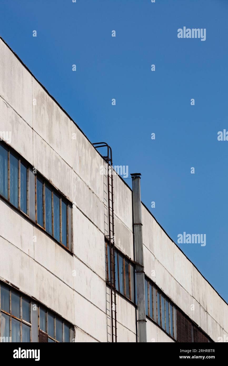 Exterior wall of an old industrial building against blue sky. Industrial site city area. Abandoned industry concept. Stock Photo