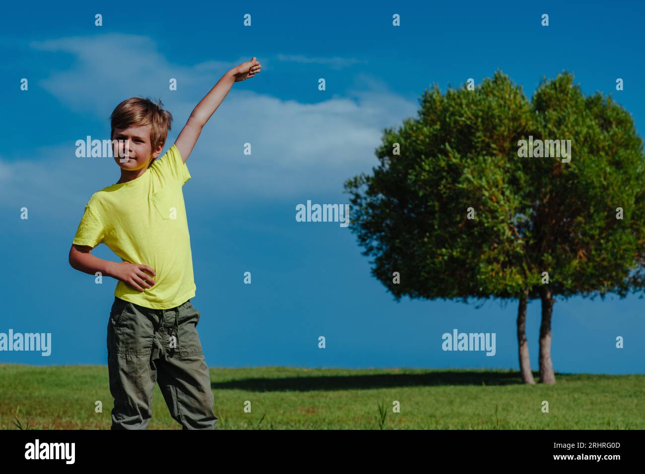 Boy showing height of the tree on a sunny day, ecology concept Stock Photo