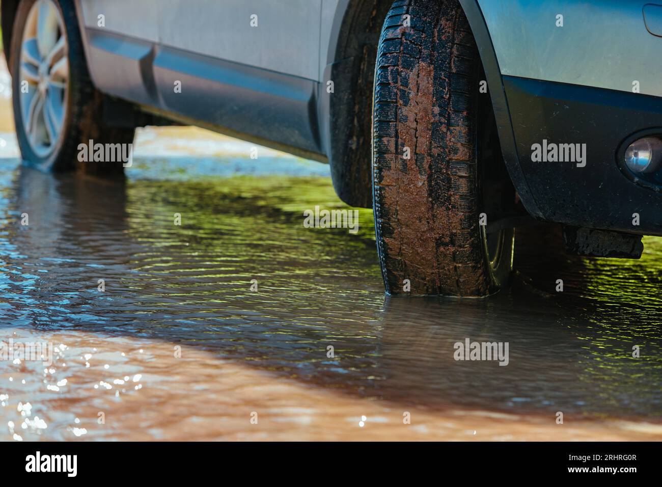 Car wheel standing offroad in a muddy puddle close-up view Stock Photo