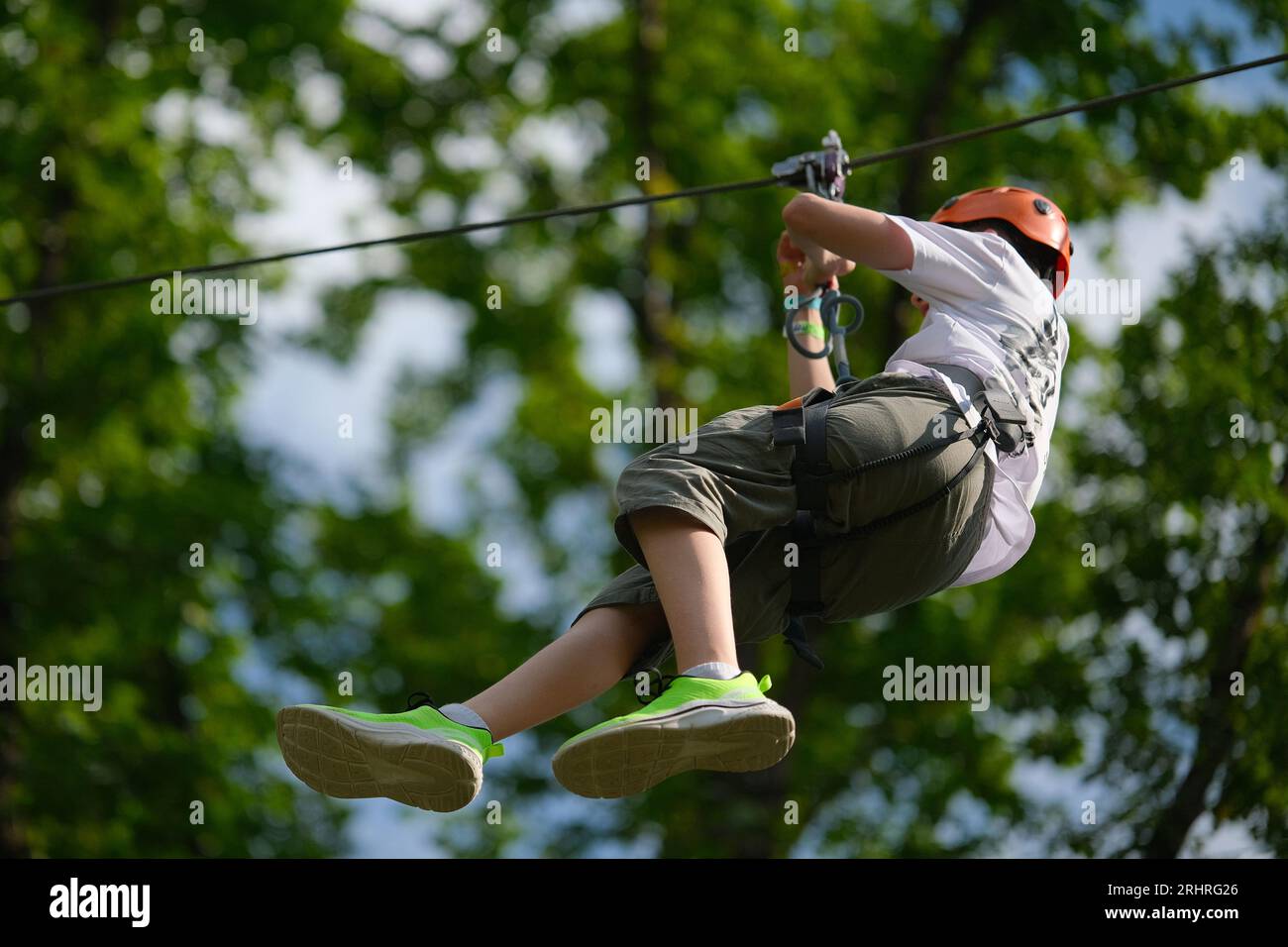 Teenage boy on zipline having fun at outdoor extreme adventure park