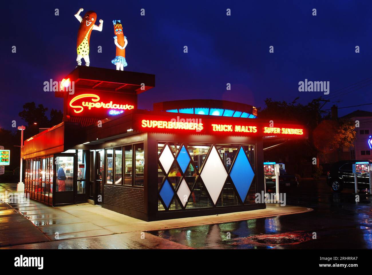 Two large human like hot dogs stand on top of Superdawg Drive In, Chicago, Illinois and are illuminated at night Stock Photo