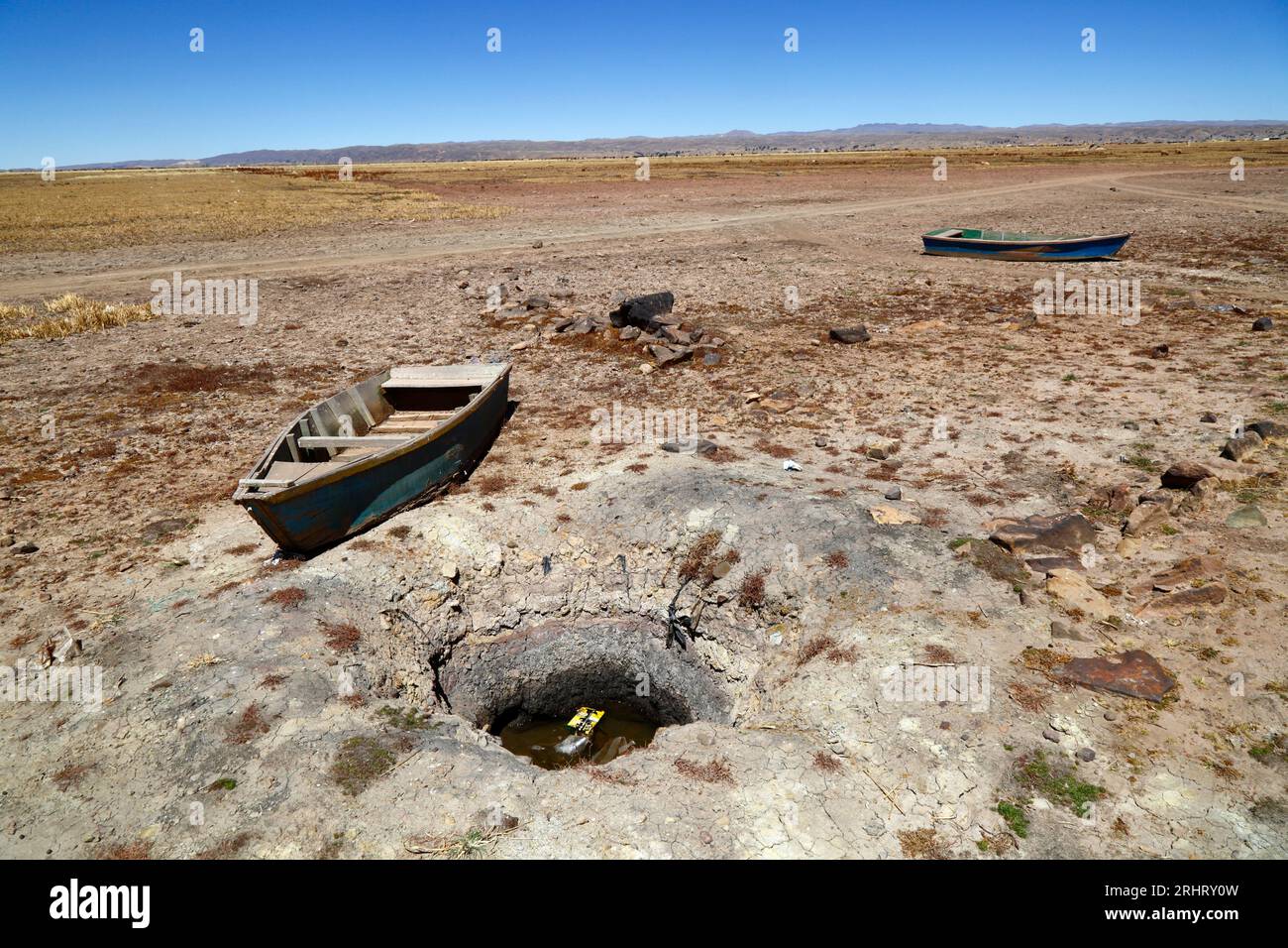 Lake Titicaca, BOLIVIA; August 18th 2023: Wooden rowing boats next to a well dug by villagers on the dried up shore of Cohana Bay on the Inner Lake / Huiñay Marka (the smaller part of Lake Titicaca) near the village of Cohana. Water levels in Lake Titicaca are approaching the record low level set in 1996, the lowest since Bolivia's weather service (Senhami) started keeping records in 1974. Many are blaming climate change; the last few years have been drier than normal and El Niño is currently strengthening in the Pacific Ocean off South America. Stock Photo