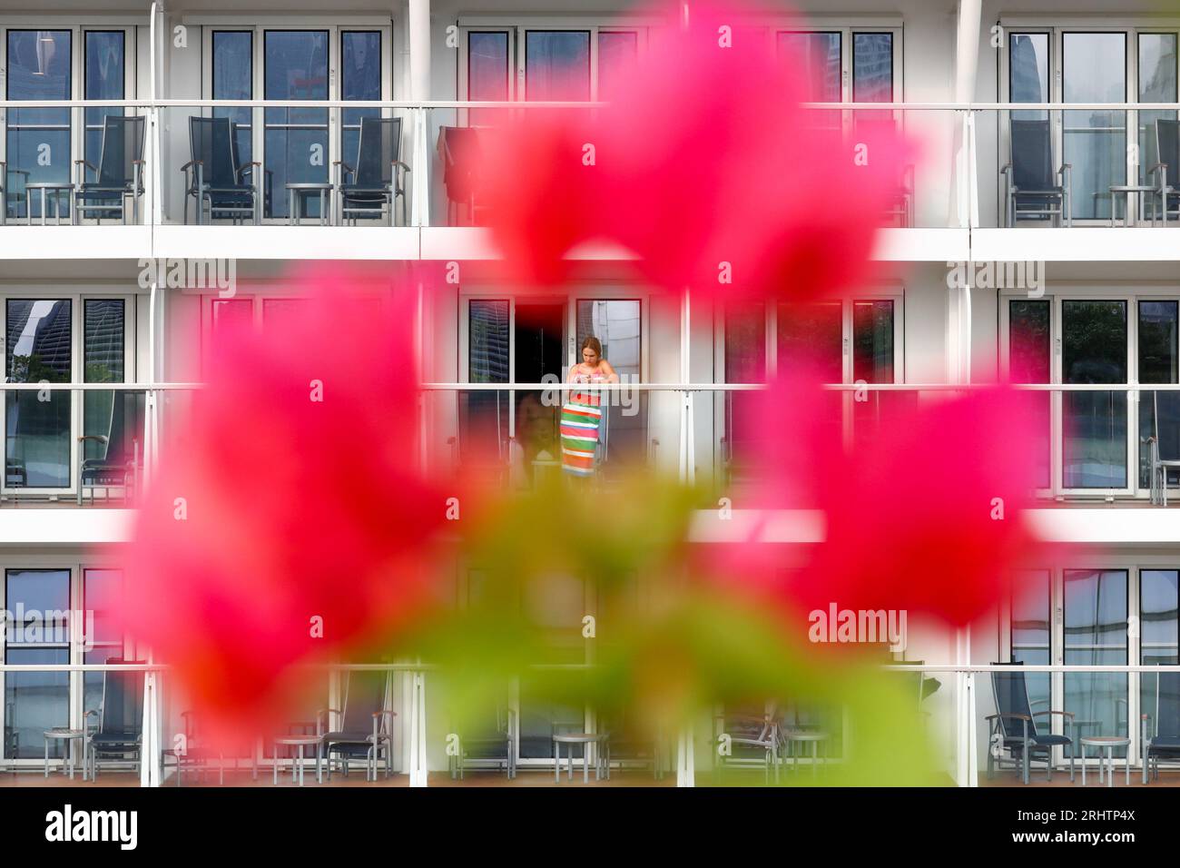 August 19, 2023, Hong Kong, Hong Kong, Hong Kong: A female tourist is seen using her phone through a flower as cruise ship SPECTRUM OF THE SEAS with nearly 4000 people on board from Japan berths at Kai Tak cruise terminal. The Hong Kong government has been working on luring international travelers to the Asia's World City to boost the economy, including attracting tourists from mainland China and Southeast Asian countries by giving free cash vouchers for shopping and food. Credit: ZUMA Press, Inc./Alamy Live News Stock Photo