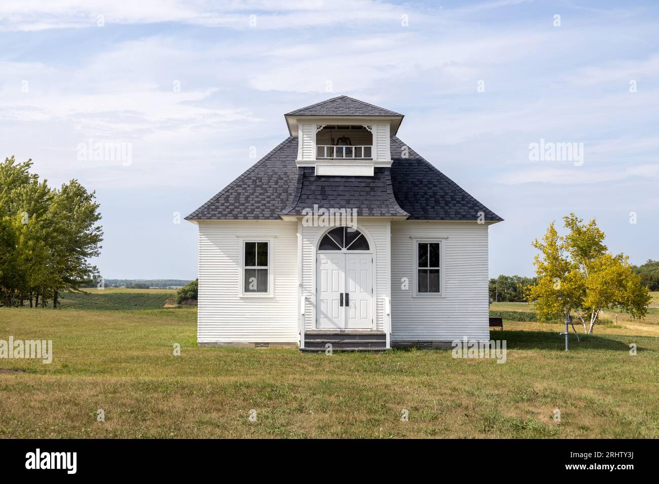 Sunny landscape view of a rural 19th century wood constructed one-room country schoolhouse situated on a prairie in midwest USA. Stock Photo