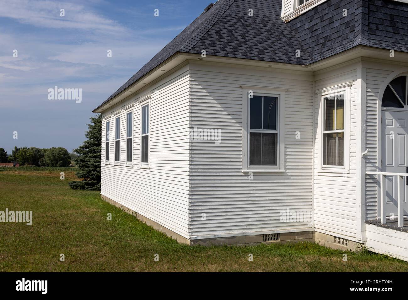 Sunny landscape view of a rural 19th century wood constructed one-room country schoolhouse situated on a prairie in midwest USA. Stock Photo