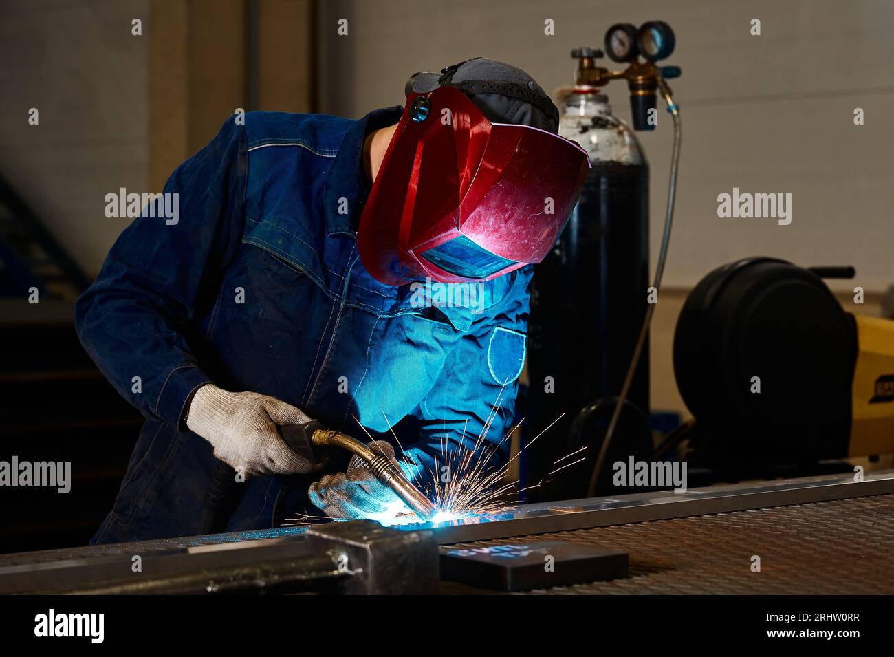 Worker with mask welds details with semi automatic machine Stock Photo