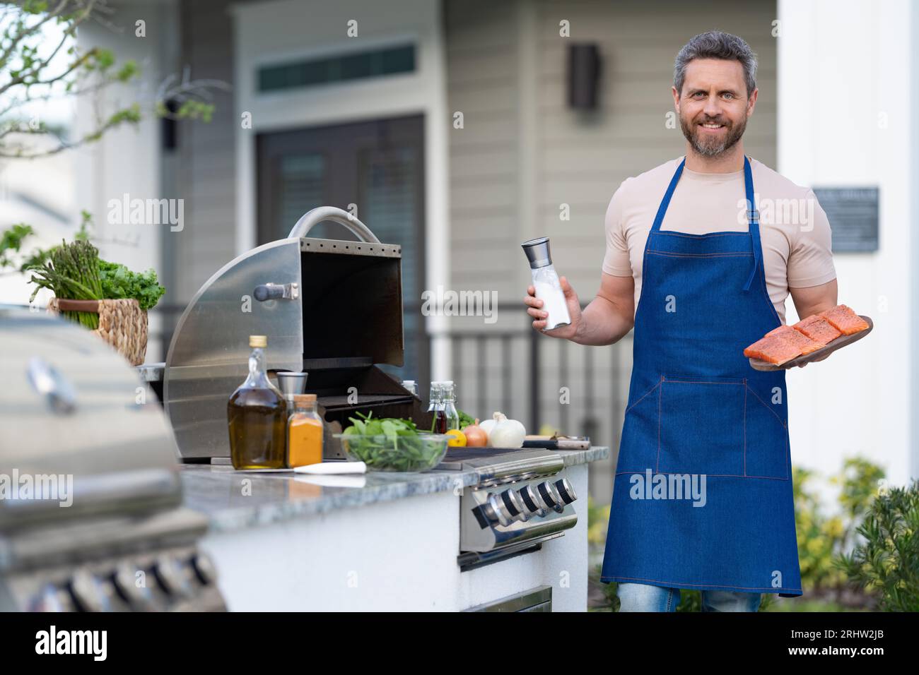 barbecue man with salmon in apron, advertisement. photo of barbecue man with salmon fish Stock Photo