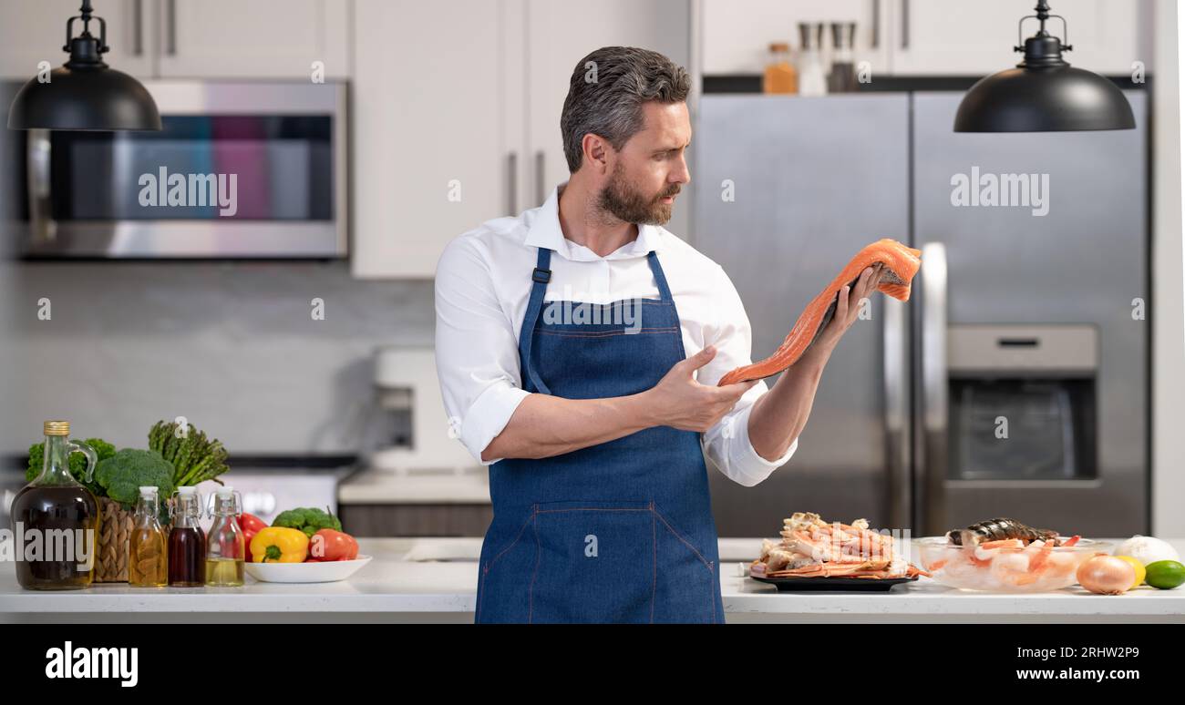 photo of chef man cooking fish wearing apron in the kitchen. Stock Photo