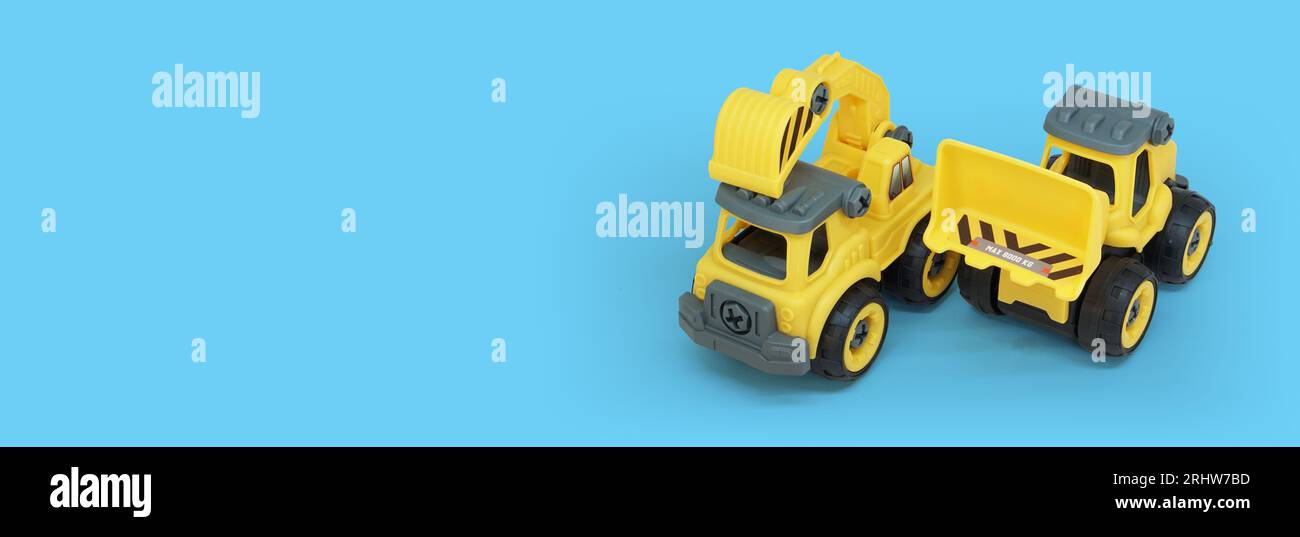 yellow plastic truck and bulldozer toy isolated on blue background with copy space for text or banner Stock Photo