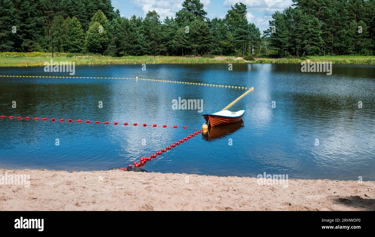 Bathing area prepared for the reception of sunbathers. An empty boat and floating buoys marking a place for swimming. Jacnia, Poland Stock Photo