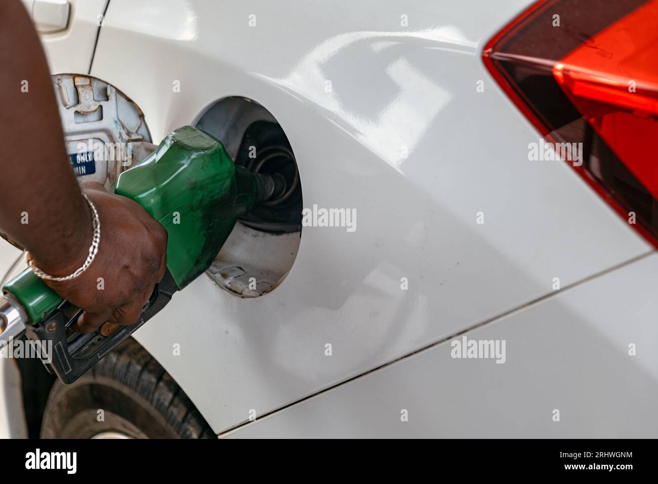 A petrol bunk attendant is filling petrol into the fuel tank of a car
