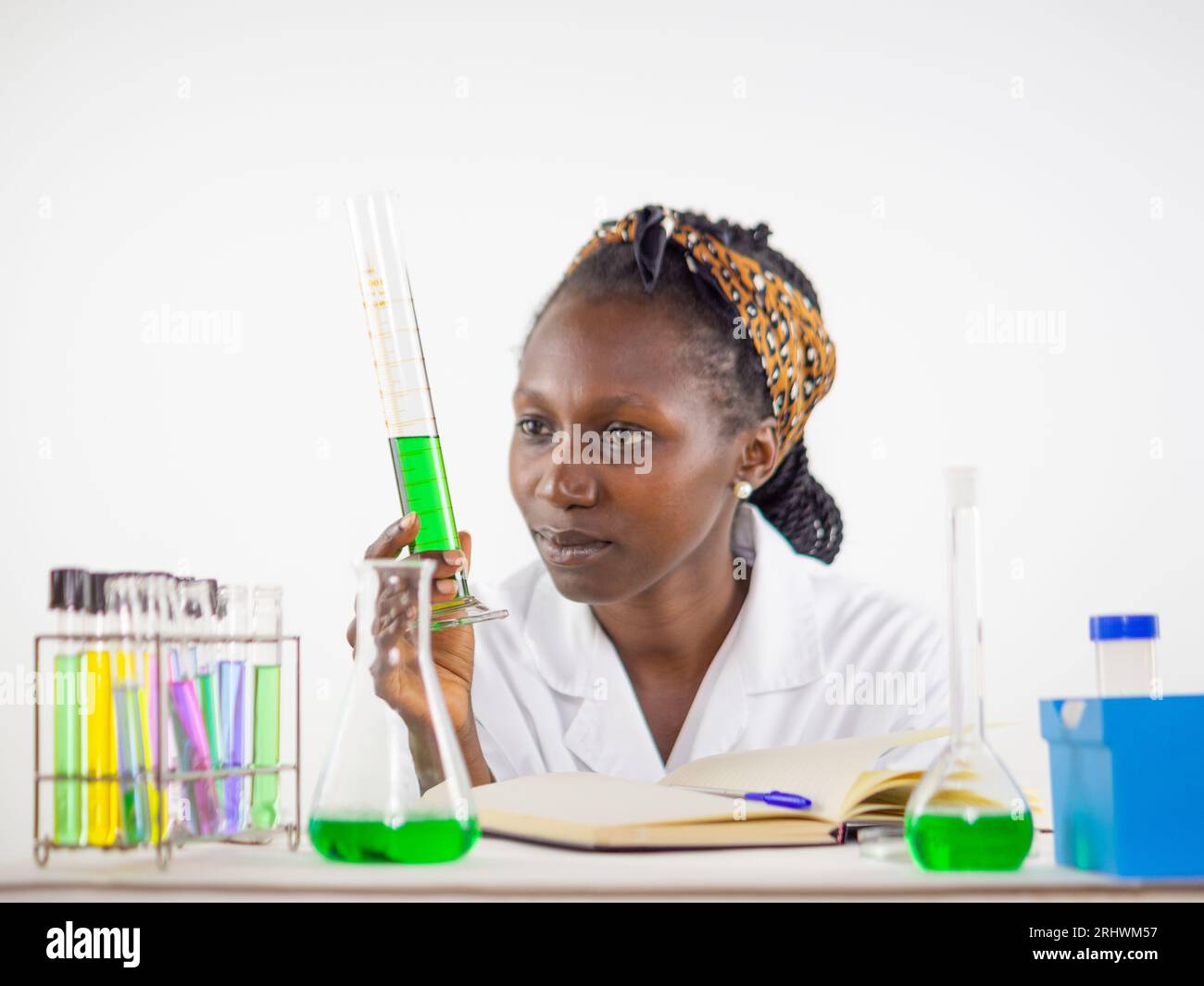 Young female scientist keenly observing a liquid sample held measuring cylinder while in a laboratory Stock Photo