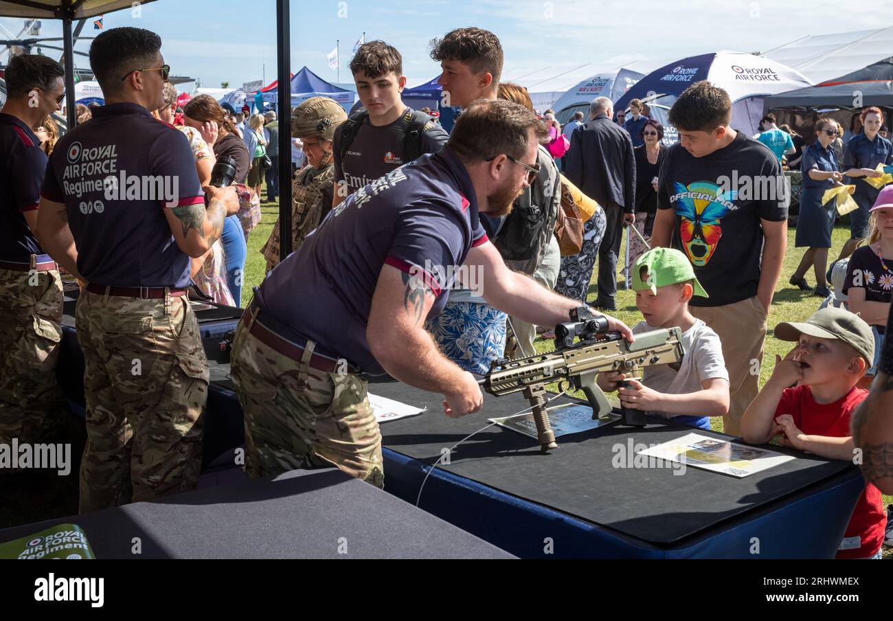 Eastbourne, UK. 19 Aug 2023. A young boy is shown a miliatry rifle by a soldier from the RAF Regiment at a display stand in the military exhibition alongside the annual Eastbourne Airbourne, an international airshow. The show runs for four days with flying displays along the seafront. Credit: Andy Soloman/Alamy Live News Stock Photo