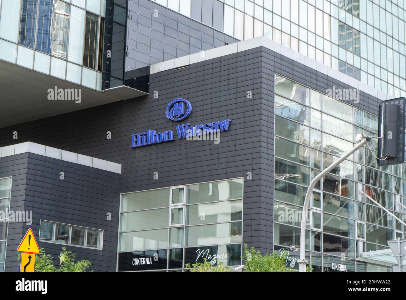 The building and logo of the Polish hotel Hilton Warsaw. Office building skyscraper in the city center. Entrance facade. Warsaw, Poland - July 26, 2023. Stock Photo