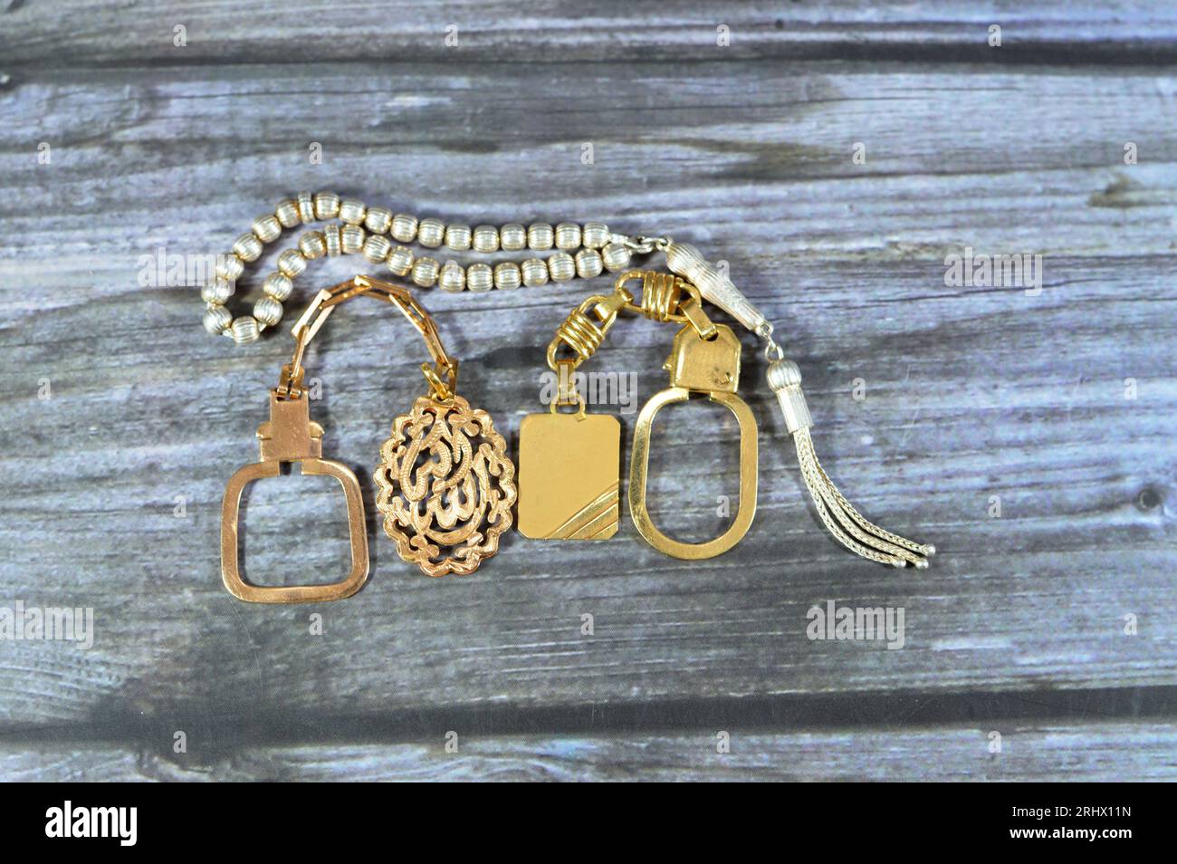 A silver rosary and golden keyring medals made of gold karat 18 with an Arabic text on one of them Allahu Akbar translation (God is the greatest), gol Stock Photo